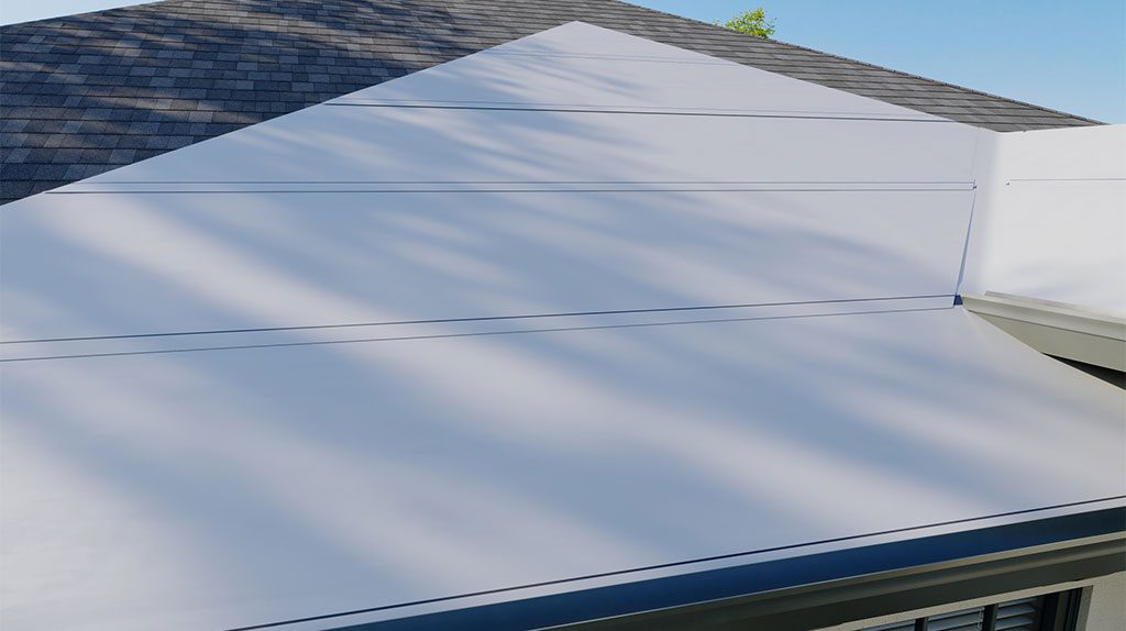 A house features a flat white roof extension beneath a sloped section with gray shingles. Shadows from nearby trees are cast on the roof in the sunlight.