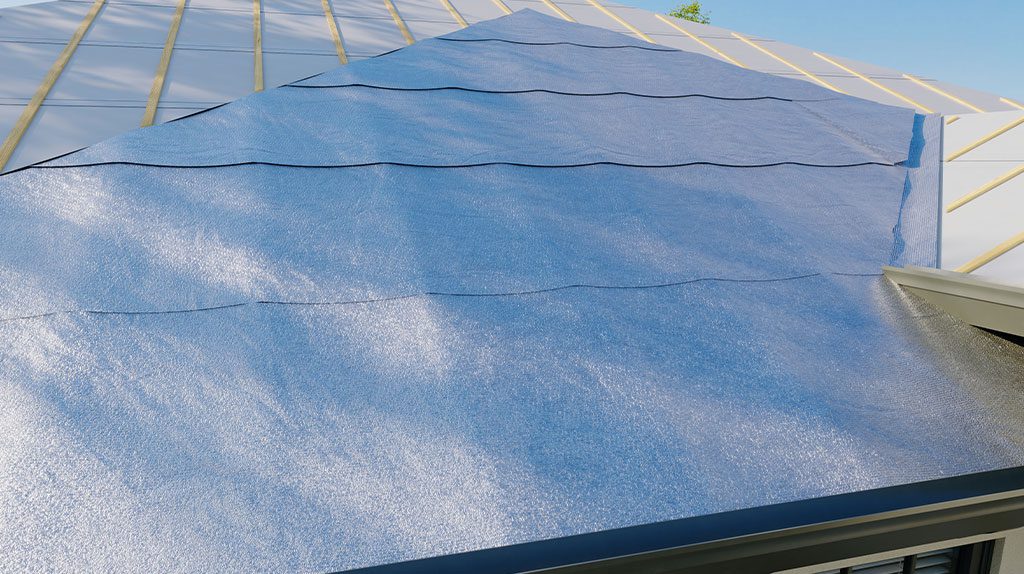 Blue roofing underlayment installed over a roof frame, with visible overlapping strips and metal edges, beneath a clear sky.