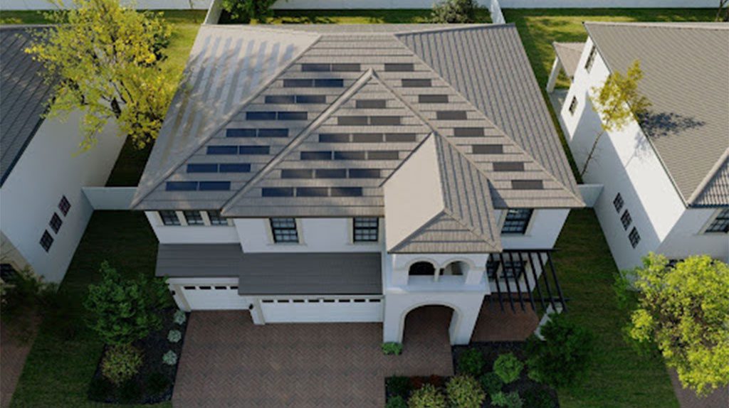 Aerial view of a two-story house with solar panels on the roof, surrounded by a driveway and landscaped garden.